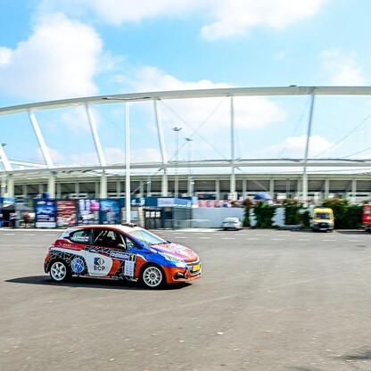 Rozświetlona scena Rajdu Śląska z rajdowcem na tle Superauto.pl Stadionu Śląskiego. (wygenerowano przez AI)