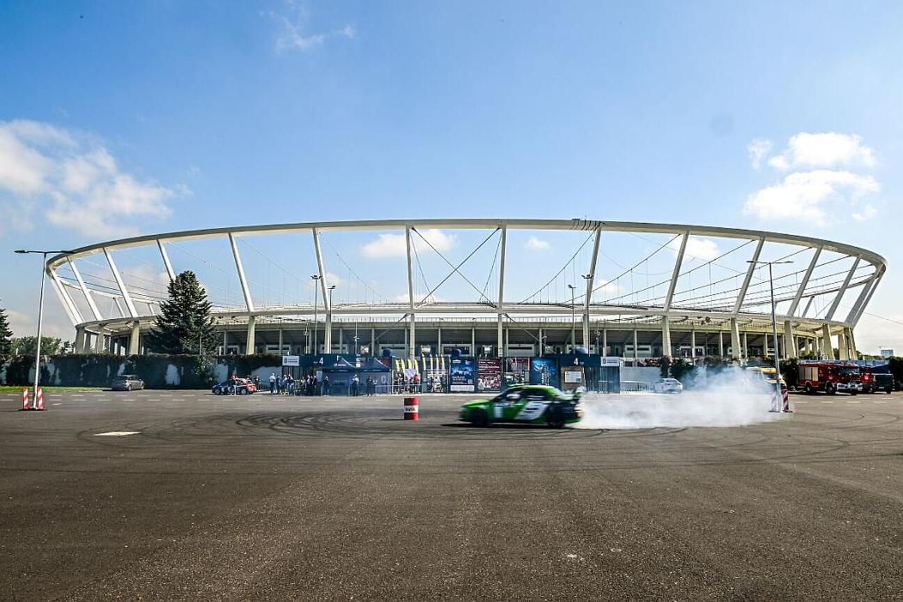 Rally car z hashtagiem #rajdslaska i logo European Rally Trophy, stojące przed Stadionem Śląskim w Katowicach. (wygenerowano przez AI)