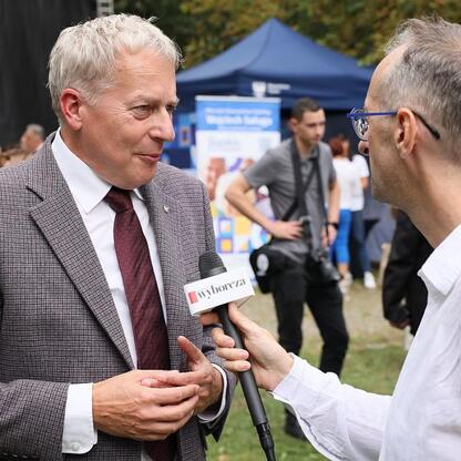 Marszałek Wojciech Saługa w rozmowie z dziennikarzem na Targach Silver Silesia. (wygenerowano przez AI)
