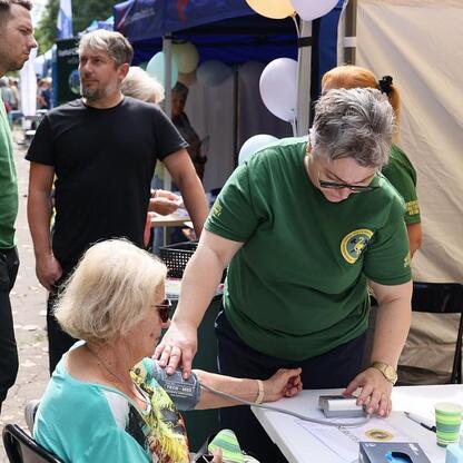 Na Silver Silesia trade fair, kobieta pomaga starszej kobiecie w pomiarze ciśnienia krwi, demonstrując dostępne usługi zdrowotne. (wygenerowano przez AI)