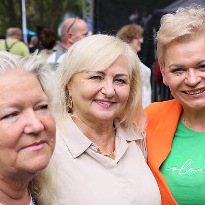 Zdjęcie przedstawia aktywną atmosferę na Targach Silver Silesia, gdzie grupa seniorów cieszy się i rozmawia w otwartym, zielonym miejscu. (wygenerowano przez AI)
