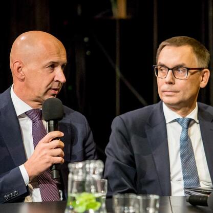 Podczas panelu dyskusyjnego na Śląskim Stole w Teatrze Śląskim, dwaj uczestnicy dyskutują o promocji regionu, mikrofon w ręce jednego z nich. (wygenerowano przez AI)