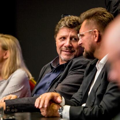 Grupa ludzi dyskutuje o rozwoju Śląska, siedząc przy stole w Teatrze Śląskim. (wygenerowano przez AI)