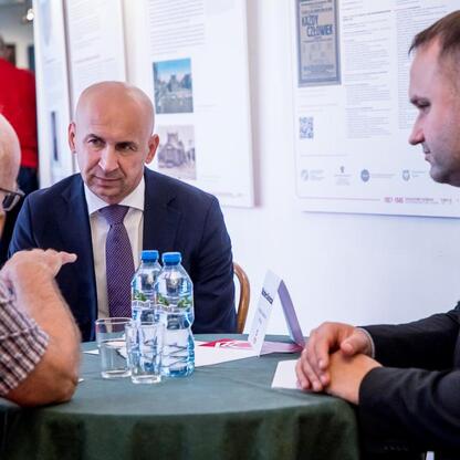 Trzy osoby w rozmowie na Śląskim Stole, Teatr Śląski, rozmowa o regionalnym rozwoju i kulturze. (wygenerowano przez AI)