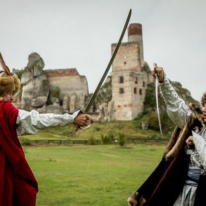 Dramatyczna scena z mieczami przed historycznym zamkiem, reprezentująca filmowe widowisko Juromania. (wygenerowano przez AI)