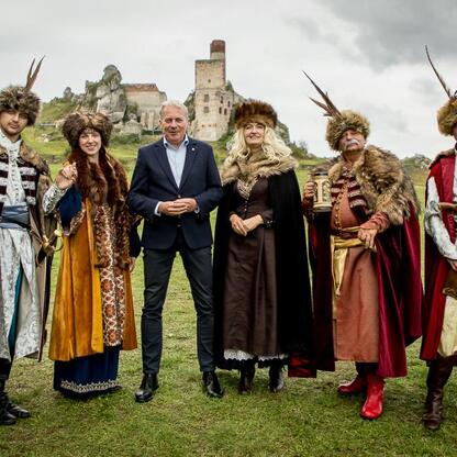 Grupa ludzi w strojach historycznych przed ruiny zamku, rekonstrukcja średniowiecza, Juromania. (wygenerowano przez AI)