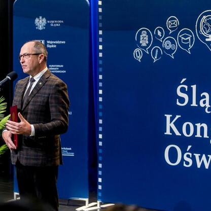 Podczas Śląskiego Kongresu Oświaty w Katowicach, na podium stoi mówca, prezentujący nowe trendy w edukacji. (wygenerowano przez AI)