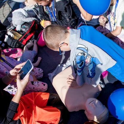Grupa dzieci uczestniczy w aktywności edukacyjnej na jubileuszu Sosnowieckiego Pogotowia Ratunkowego. (wygenerowano przez AI)