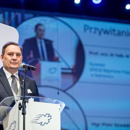 Uroczystość 30-lecia SPZOZ Rejonowego Pogotowia Ratunkowego w Sosnowcu. Mężczyzna w garniturze przemawia na podium, tło: 