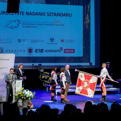 Uroczystość 30-lecia SPZOZ Rejonowego Pogotowia Ratunkowego w Sosnowcu, z udziałem marszałka Wojciecha Saługi i dyrektora Klaudiusza Nadolnego, odbyła się w Pałacu Kultury Zagłębia w Dąbrowie Górnicze (wygenerowano przez AI)