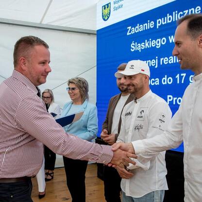 Wicemarszałek Leszek Pietraszek i przedstawiciele klubów sportowych podczas symbolicznych prezentacji czeków na Superauto.pl Stadionie Śląskim. (wygenerowano przez AI)