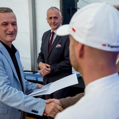 Wicemarszałek Leszek Pietraszek wręcza symboliczne czeki przedstawicielom 154 klubów sportowych na Superauto.pl Stadion Śląskim. (wygenerowano przez AI)