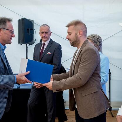 Wicemarszałek Leszek Pietraszek i przedstawiciele klubów sportowych podczas symbolicznych prezentacji czeków na Superauto.pl Stadionie Śląskim. (wygenerowano przez AI)