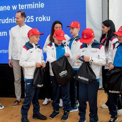 Grupa młodych sportowców z Superauto.pl Stadium Śląskim otrzymuje symboliczne czeki w ramach Programu Klub. (wygenerowano przez AI)