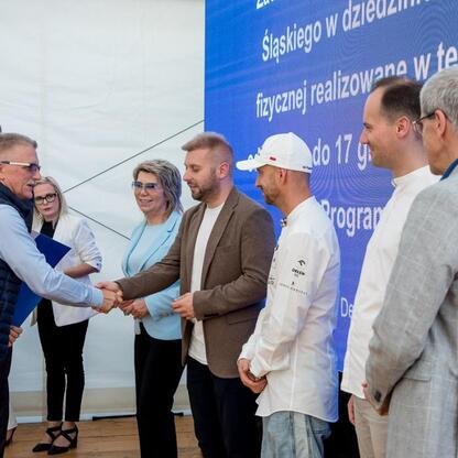 Wicemarszałek Leszek Pietraszek i przedstawiciele Silesia podczas symbolicznych prezentacji czeków dla 154 klubów sportowych w Superauto.pl Stadionie Śląskim. (wygenerowano przez AI)