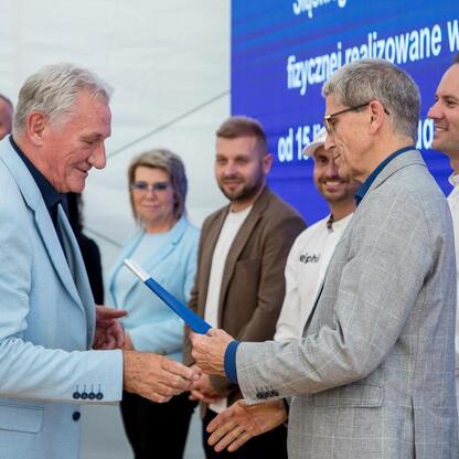 Wicemarszałek Leszek Pietraszek prezentuje symboliczne czeki przedstawicielom 154 klubów sportowych na Superauto.pl Stadionie Śląskim. (wygenerowano przez AI)