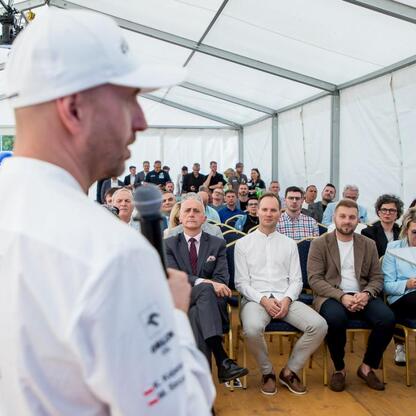 Wicemarszałek Leszek Pietraszek prezentuje symboliczne czeki przedstawicielom 154 klubów sportowych na Superauto.pl Stadion Śląskim. (wygenerowano przez AI)