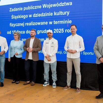 Wicemarszałek Leszek Pietraszek i przedstawiciele klubów sportowych podczas symbolicznych prezentacji czeków na Stadionie Śląskim. (wygenerowano przez AI)