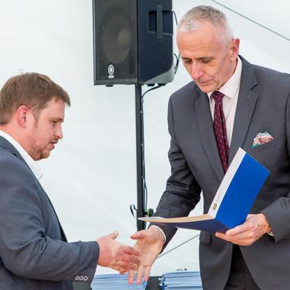 Wicemarszałek Leszek Pietraszek prezentuje symboliczne czeki przedstawicielom 154 klubów sportowych na Superauto.pl Stadionie Śląskim. (wygenerowano przez AI)