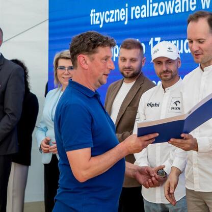 Wicemarszałek Leszek Pietraszek wręcza symboliczne czeki przedstawicielom 154 klubów sportowych na Superauto.pl Stadionie Śląskim. (wygenerowano przez AI)