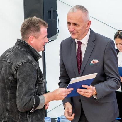 Wicemarszałek Leszek Pietraszek wręcza symboliczne czeky przedstawicielom klubów sportowych na Superauto.pl Stadion Śląskim. (wygenerowano przez AI)