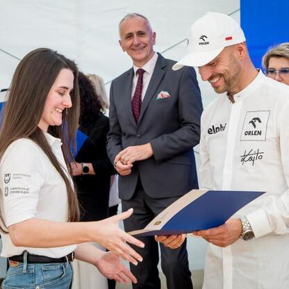 Wicemarszałek Leszek Pietraszek wręcza symboliczne czeky przedstawicielom klubów sportowych podczas uroczystości w Superauto.pl Stadion Śląskim. (wygenerowano przez AI)