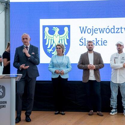 Wicemarszałek Leszek Pietraszek i przedstawiciele klubów sportowych podczas symbolicznych prezentacji czeków na Stadionie Śląskim. (wygenerowano przez AI)