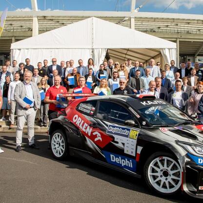 Grupa przedstawicieli klubów sportowych i lokalnych władz z udziałem Kajetana Kajetanowicza podczas ceremonii symbolicznego prezentowania czeków na Superauto.pl Stadionie Śląskim. (wygenerowano przez AI)