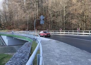 Nowoczesny most pieszy z zielonym przepustem bezpieczeństwa, znak T-junction i oznakowanie drogi, w ramach modernizacji DW 948. (wygenerowano przez AI)