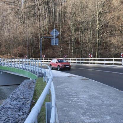Nowoczesny most pieszy z zielonym przepustem bezpieczeństwa, znak T-junction i oznakowanie drogi, w ramach modernizacji DW 948. (wygenerowano przez AI)