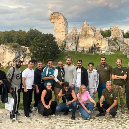 Grupa osób wizytuje ruiny Zamek Ogrodzieniec w Polsce, omawiając potencjał turystyczny i biznesowy regionu. (wygenerowano przez AI)