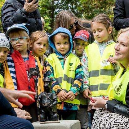 Grupa osób uczestniczących w uroczystości odsłonięcia symbolicznego Geodezjusza Śląskiego w parku Kościuszki. (wygenerowano przez AI)