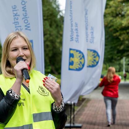Joanna Bojczuk, członkini Zarządu Województwa Śląskiego, przemawia na mikrofonie podczas uroczystości w Katowicach. (wygenerowano przez AI)
