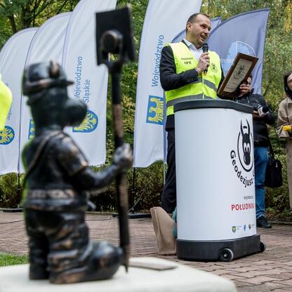 Na podium w parku Kościuszki odsłonięto figurkę Geodezjusza Beboka, symbolizującego geodety i ich rolę w regionie Śląskim. (wygenerowano przez AI)