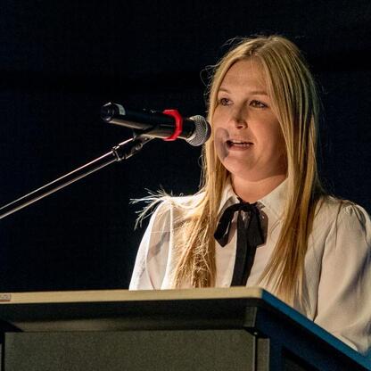 Wojewódzkie Obchody Światowego Dnia Turystyki w Tarnowskich Górach. Joanna Bojczuk, Członkini Zarządu Województwa Śląskiego, przemawia na podium podczas uroczystości. (wygenerowano przez AI)