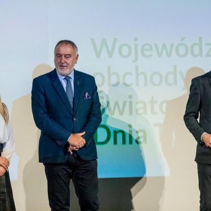 Na Wojewódzkich Obchodach Światowego Dnia Turystyki w Silesia nagrodzono osoby za zasługi w rozwoju turystyki. Na scenie otrzymali dyplomy, symbolizujące ich wkład w promocję turystyki i kulturowej dz (wygenerowano przez AI)
