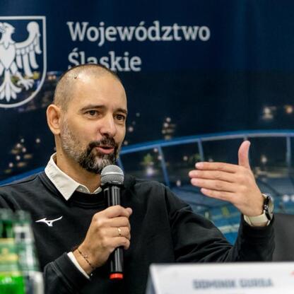 Mężczyzna przemawia na konferencji prasowej, omawiając Silesia Marathon. (wygenerowano przez AI)