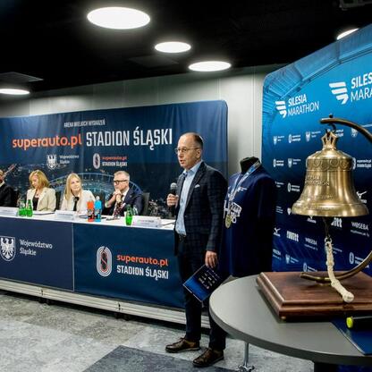 Na zdjęciu: Joanna Bojczuk, członkini zarządu województwa śląskiego, przemawia na konferencji prasowej w Superauto.pl Stadion Śląski, podczas 17. edycji Silesia Marathon. (wygenerowano przez AI)