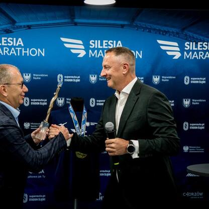 Celebracja 17. edycji Silesia Marathonu: dwie osoby wymieniają trofeum, symbolizując sukces i społeczne zaangażowanie. (wygenerowano przez AI)