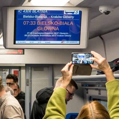 Wnętrze pociągu IC 4306 Błatnia, wyświetlacz informuje o wyjściu z Bielska-Białej do Krakowa. (wygenerowano przez AI)