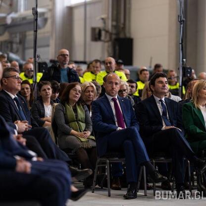 Zdjęcie przedstawia konferencję prasową w hali produkcyjnej Bumar-Łabędy w Gliwicach, związana z podpisaniem kontraktu na budowę nowoczesnego centrum produkcji pojazdów opancerzonych. (wygenerowano przez AI)