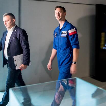 Astronauta w niebieskim garniturze spaceruje po wystawie w Planetarium Śląskiego, promując misję IGNIS. (wygenerowano przez AI)