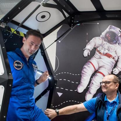 Astronauta w niebieskim strój kosmiczny demonstruje model astronauty, inspirując młode pokolenie w Śląskim Parku Nauki. (wygenerowano przez AI)