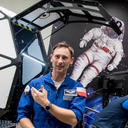 Astronauta w niebieskim mundurze prezentuje się wokół kosmicznego modelu,激励着年轻一代探索太空。 (wygenerowano przez AI)