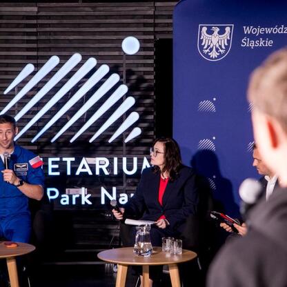 Panel dyskusyjny w Śląskim Planetarium, gdzie astronauta Sławosz Uznański-Wiśniewski inspiruje młodych uczestników. (wygenerowano przez AI)