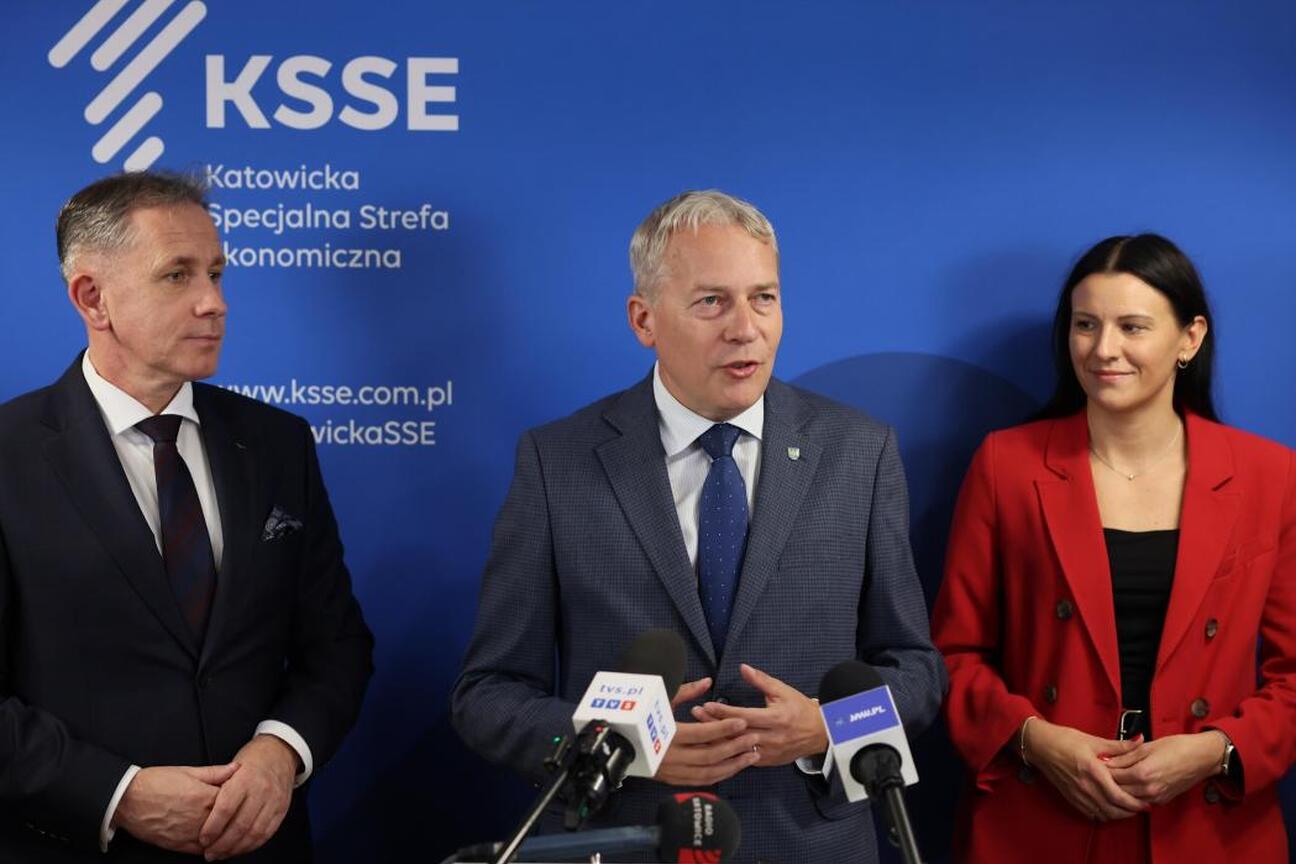 Marszałek Wojciech Saługa przemawia na podium podczas konferencji prasowej, podkreślając sukces Katowickiej Specjalnej Strefy Ekonomicznej w konkursie Financial Times. (wygenerowano przez AI)
