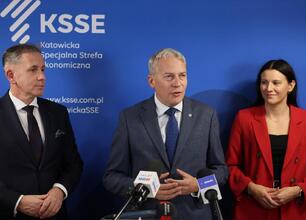Marszałek Wojciech Saługa przemawia na podium podczas konferencji prasowej, podkreślając sukces Katowickiej Specjalnej Strefy Ekonomicznej w konkursie Financial Times. (wygenerowano przez AI)
