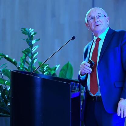 Mężczyzna w garniturze i krawacie przemawia na podium podczas konferencji na Śląsku, omawiając przyszłość regionu w kontekście transformacji energetycznej. (wygenerowano przez AI)