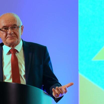 Mężczyzna w garniturze przemawia na podium podczas konferencji 