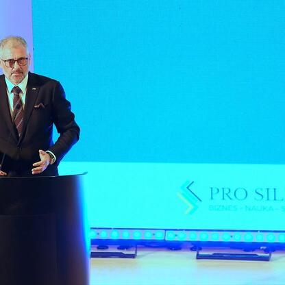 Mężczyzna w garniturze przemawia na podium podczas konferencji 